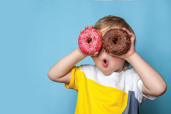 boy with two donuts held over his eyes