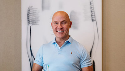 Man smiling in front of picture of toothbrushes
